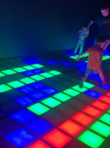 Niños y niñas corriendo sobre el piso iluminado de Piso es Lava
