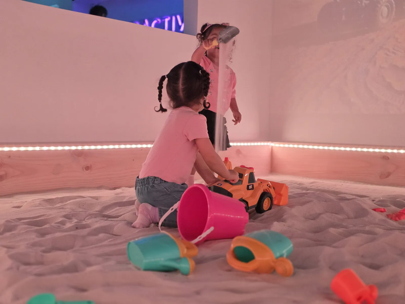Niños y niñas juegan con excavadoras de juguete en el sandbox
